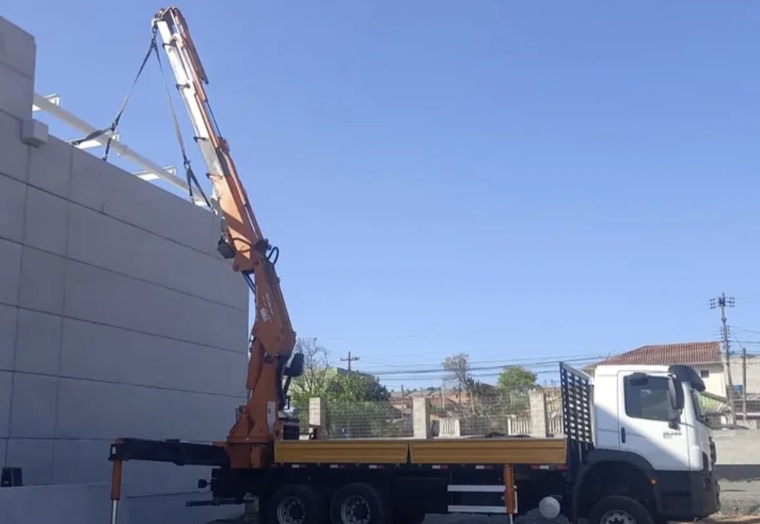 Guindaste da Sua Empresa içando carga junto a estrutura industrial